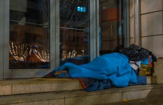 Eine Peron liegt mit Decken bedeckt und Taschen auf einer Treppe.