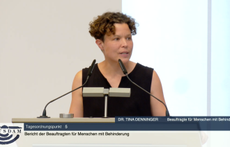 Das Bild zeigt Dr. Tina Denninger, Beauftragte für Menschen mit Behinderung der Landeshauptstadt Potsdam, bei einem Redebeitrag am Redepult während einer Sitzung der Stadtverordnetenversammlung (SVV). Sie spricht zum Tagesordnungspunkt 5 mit dem Titel „Bericht der Beauftragten für Menschen mit Behinderung“. Im Bild ist sie gestikulierend zu sehen, was auf ein engagiertes und erklärendes Sprechen hindeutet. Am unteren Bildrand ist das offizielle Potsdam-Logo eingeblendet.