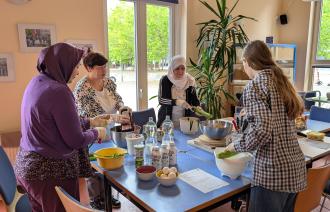 Vier Frauen bereiten an einem Tisch ein Gericht zu.