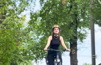 Eine Frau sitzt auf einem Fahrrad und fährt der Kamera entgegen.
