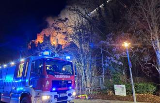 Ein Feuerwehrauto steht vor der brennenden Villa.