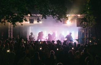 Eine Band auf der Bühne im Lindenpark spielt vor einer breiten Masse.