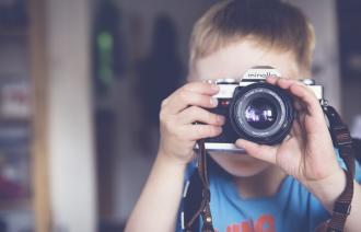 Ein Kind hält eine Kamera in der Hand und fotografiert die Person, die das Foto macht.