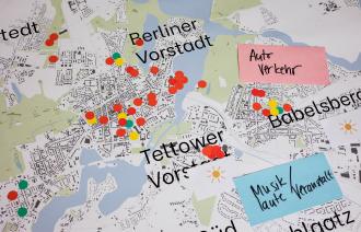 Das Bild zeigt einen Ausschnitt der Stadtkarte Potsdams mit den Bereichen Berliner Vorstadt, Babelsberg und Teltower Vorstadt, auf dem mehrere runde Aufkleber in grüner, roter und gelber Farbe und zwei Zettel mit den Aufschriften "Autoverkehr" und "Musik / laute Veranstaltungen" verteilt sind. Mit dieser Karte hat man im Rahmen des Runden Tisches das Kulturangebot in den unterschiedlichen Stadtteilen Potsdams evaluiert.