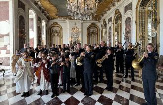 Im prächtigen Saal von Schloss Sanssouci musizieren viele uniformierte Berufsmusiker*innen und Kinder in historischen Gewändern