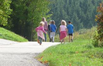 Eine Familie läuft auf einem Weg, der von grünen Flächen gerahmt ist