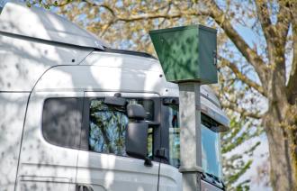 Ein Blitzer in einer Straße, an dem ein LKW vorbeifährt.