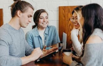 Vier Menschen am Tisch, die sich anlächeln