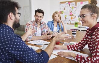 Vier Personen sitzen an einem Tisch in Workshop-FOrm.
