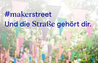 Schrift über Wimpeln, die in den Bäumen gespannt sind.