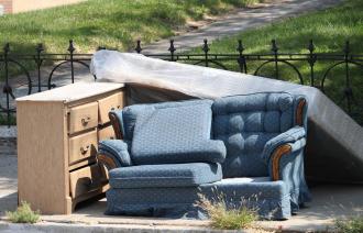 Eine Kommode, eine blaue Couch und eine Matratze liegen am Straßenrand.