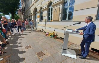 Oberbürgermeister Mike Schubert steht vor dem Geburtshaus von Max Dortu in der Dortustraße und spricht zu Gästen der Gedenkveranstaltung.