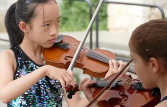 Zwei Junge Mädchen spielen Violine unter freiem Himmel