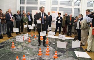 Der Obermeister Mike Schubert erläutert mit Fähnchen die wichtigsten Projekte der Zukunft auf einem Stadtteppich (Foto: Landeshauptstadt Potsdam / Barbara Plate)
