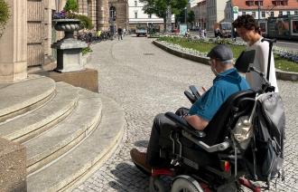 Das Foto zeigt einen Rollstuhlfahrer mit der Beauftragten für Menschen mit Behinderung, Dr. Tina Denninger