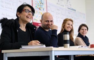 Das Foto zeigt vier an einem Tisch sitzende Personen mit Arbeitsunterlagen.