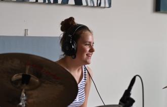 Jugendliche sitzt hinter einem Schlagzeug - Tonstudioaufnahme - Lächeln während einer Pause