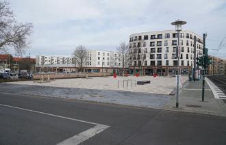 Das Bild zeigt ie Fläche des Johan-Bouman-Platzes, links eine Reihe von Sitzbänken,im Hintergrund Häuser mit Ladengeschäften.
