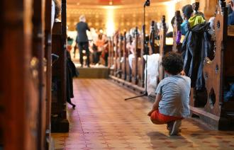 Ein Junge hockt im Gang zwischen den Sitzreihen der Erlöserkirche in Potsdam. Er ist fasziniert vom Klang des Jugendsiinfonieorchesters, das im Hintergrund nur unscharf zu sehen ist