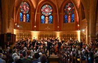 Vor der golden anmutenden Kulisse der Erlöserkirche erhebt sich das Jugendsinfonieorchester der Städtischen Musikschule Potsdam zum verdienten Applaus.