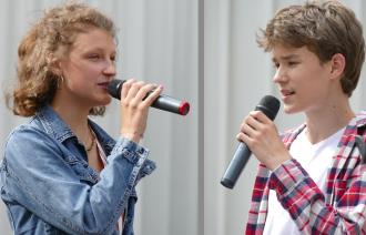 zwei Jugendliche - junge Frau und junger Mann - singen mit Mikrofonen Pop Songs