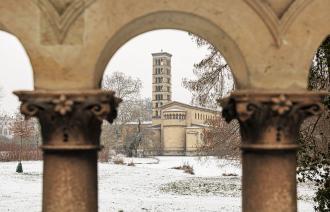 Verschneiter Park mit Kirchturm im Hintergrund, gesehen durch leicht unscharfe steinerne Bögen und Säulen im Vordergrund., Foto: André Stiebitz, Lizenz: PMSG