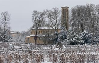 Verschneiter Park mit Hecken und kahlen Bäumen, rechts eine Kirche mit separat stehendem Kirchturm unter grauem Himmel., Foto: André Stiebitz, Lizenz: PMSG