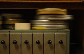 Gestapelte Filmrollen in Metallbüchsen auf einem Regal, darunter Schubladen mit schwarzen Knöpfen., Foto: Julia Nimke, Lizenz: PMSG