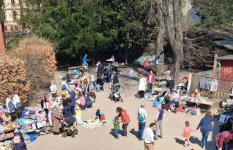 Flohmarkt im Freien mit Ständen für Kleidung und Spielzeug, viele Erwachsene und Kinder auf einem Platz unter Bäumen., Foto: Förderverein Erlöserkita, Lizenz: Förderverein Erlöserkita