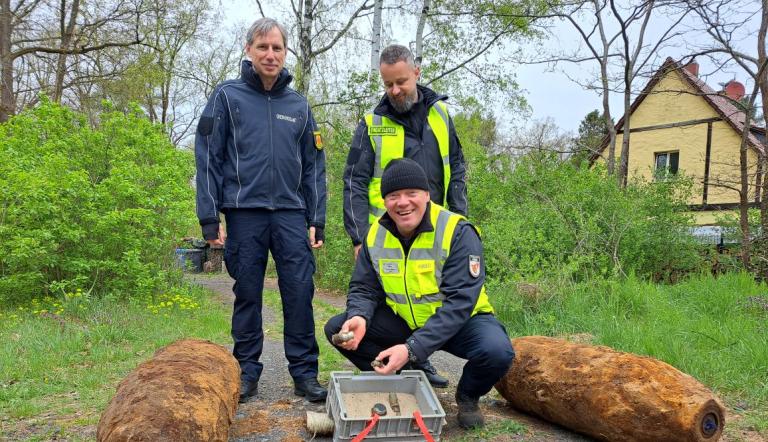 Dr. Karsten Lauber, Mike Schwitzke und Kai Lange mit den beiden entschärften Fliegerbomben am 23. April 2026