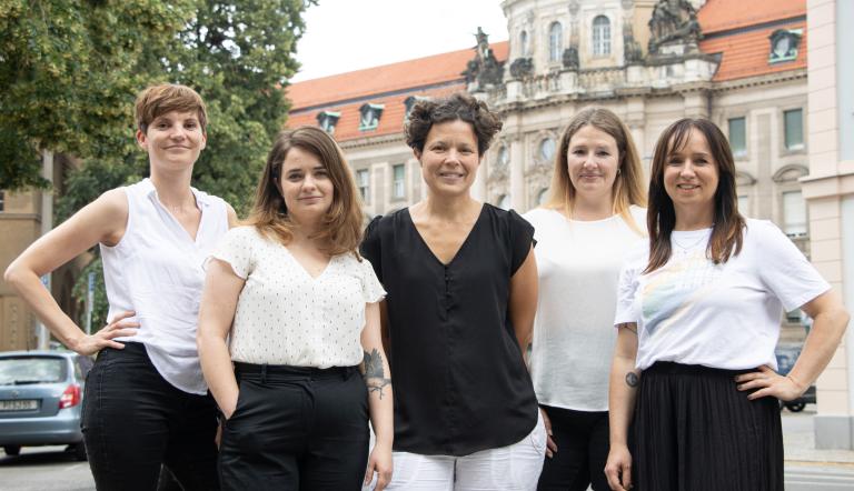 Die Teammitglieder des Büros für Chancengleichheit und Vielfalt der Landeshauptstadt Potsdam stehen auf der anderen Straßenseite vom alten Rathaus, in der Friedrich-Ebert-Straße 79/81, das alte Rathaus ist im Hintergrund zu sehen (von links nach rechts: Ina Bellmann, Claudia Sprengel, Dr. Tina Denninger, Dr. Amanda Palenberg, Stefanie Buhr)