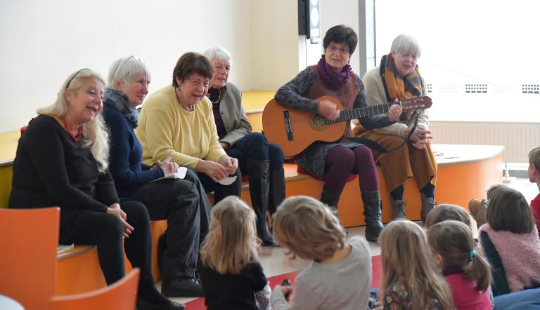 Lesepatinnen und Lesepaten lesen und spielen Kindern in der Stadt- und Landesbibliothek vor.