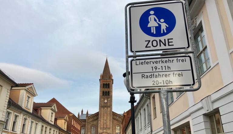 Blick in die Brandenburger Straße in Richtung St. Peter und Paul Kirche. Im Vordergrund ist das Schild "Fußgängerzone" zu sehen.