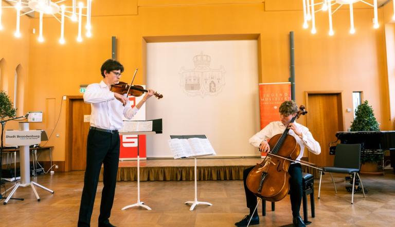 Zwei Jugendliche spielen Violine und Violoncello.