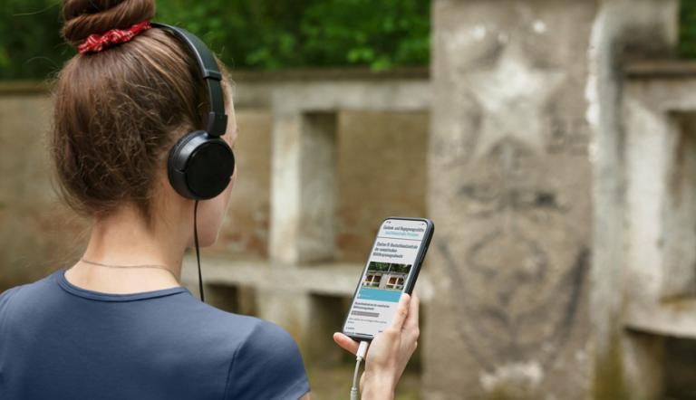 Eine Person bei einem Audiowalk durch die Gedenkstätte Leistikowstraße Potsdam