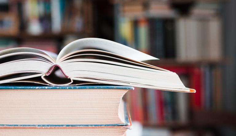 ein aufgeschlagenes Buch liegt auf anderen Büchern