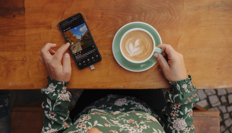Ein Cappuccino und ein Smartphone mit der Potsdam Tourismus App