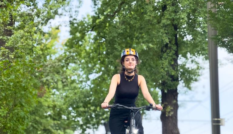 Eine Frau sitzt auf einem Fahrrad und fährt der Kamera entgegen.