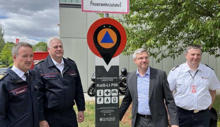Oberbürgermeister Mike Schubert und drei weitere Männer stehen neben einem Katastrophenschutz-Leuchtturm.