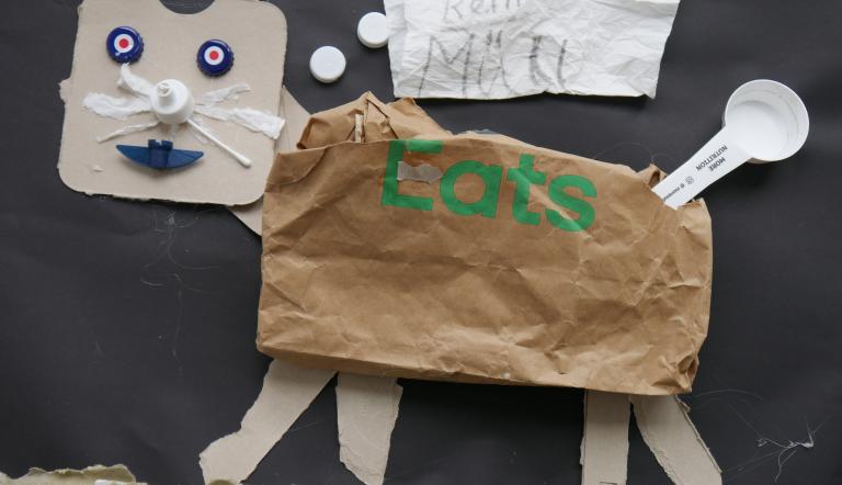 Kollage: Katze aus Papier und Pappe und verschiedenen Kunststoffverschlüssen.