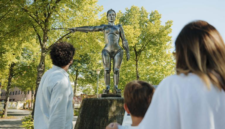 Mehrere Personen stehen vor der Metropolis-Statue im Filmpark Babelsberg