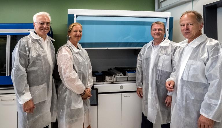 Götz Th. Friederich, Vorsitzender Wirtschaftsrat der Landeshauptstadt Potsdam, Evelyn Paschke, Geschäftsführerin Technologie- und Gewerbezentren Potsdam GmbH, Robert Loberg, Leiter Onkologie & Genetik, Roche Molecular Systems Inc., und Dr. Ruediger Ridder, Geschäftsführer Signature Diagnostics GmbH, beim Rundgang durch die neuen Labore. Foto: Potsdam Science Park Vier Personen in Schutzkleidng in einem Labor sind zu sehen.