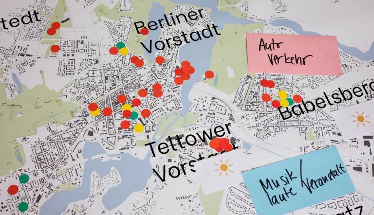 Das Bild zeigt einen Ausschnitt der Stadtkarte Potsdams mit den Bereichen Berliner Vorstadt, Babelsberg und Teltower Vorstadt, auf dem mehrere runde Aufkleber in grüner, roter und gelber Farbe und zwei Zettel mit den Aufschriften "Autoverkehr" und "Musik / laute Veranstaltungen" verteilt sind. Mit dieser Karte hat man im Rahmen des Runden Tisches das Kulturangebot in den unterschiedlichen Stadtteilen Potsdams evaluiert.