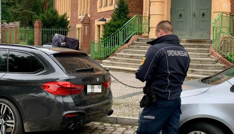 Ein Mitarbeiter des Ordnungsamtes vor einem Auto.