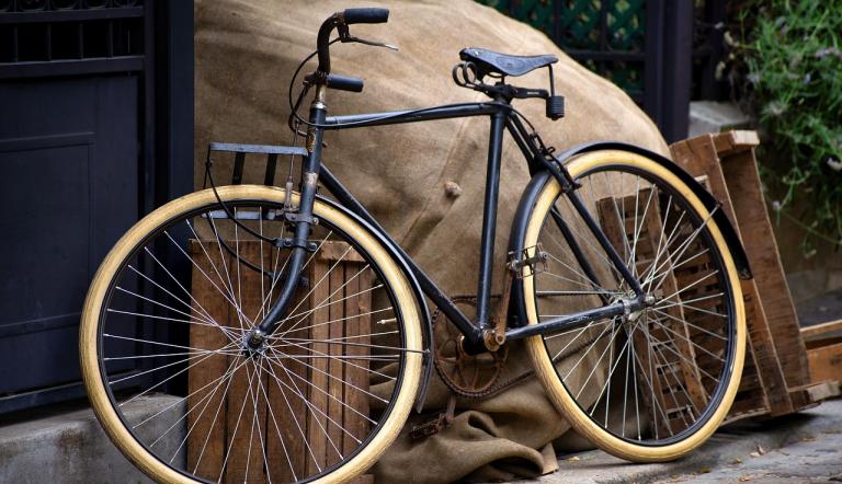 Fahrrad Ein altes schwarzes Herrenrad vor einer Hauswand, Säcken und Kisten.