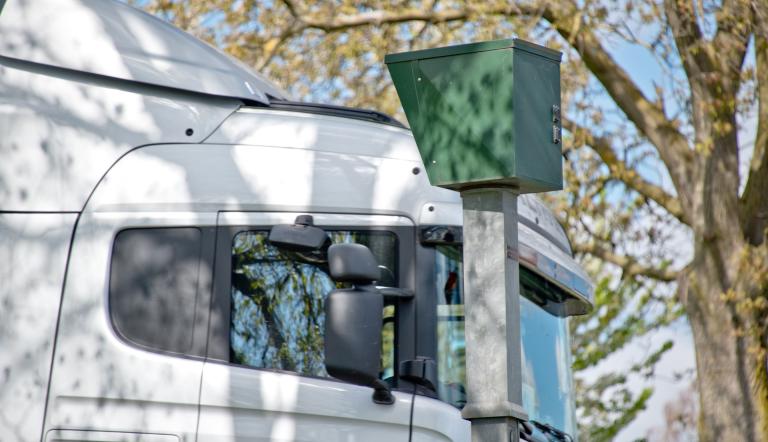 Ein Blitzer in einer Straße, an dem ein LKW vorbeifährt.