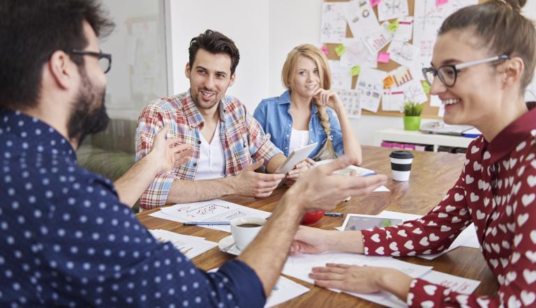Vier Personen sitzen an einem Tisch in Workshop-FOrm.