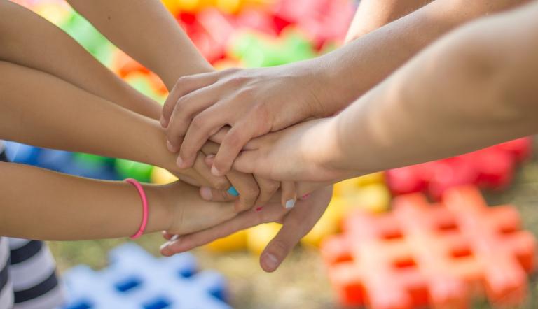Kinder- und Jugendnetzwerke Das Bild zeigt mehrere Kinderhände, die sich berühren.