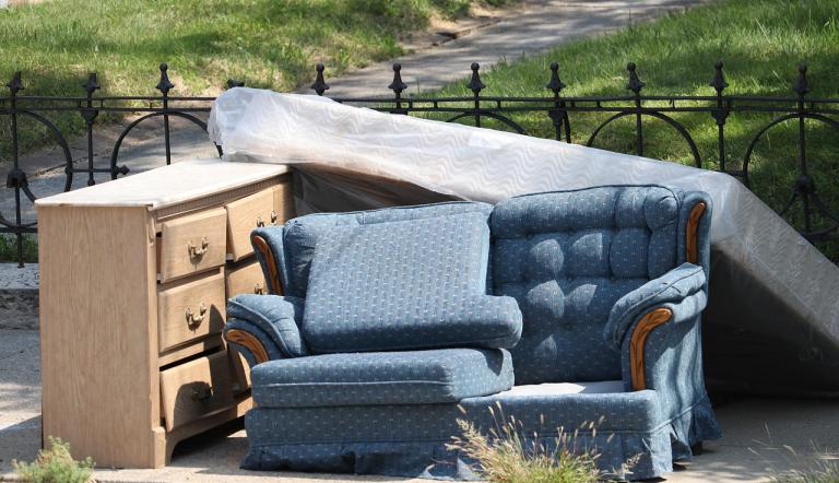 Eine Kommode, eine blaue Couch und eine Matratze liegen am Straßenrand.