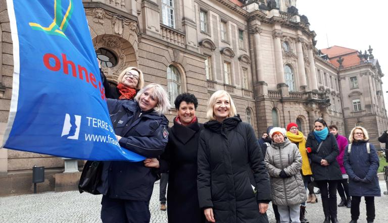 Brigitte Meier und Martina Trauth (3. und 4. v. links) hissen die Fahne TERRES DES FEMMES vor dem Potsdamer Rathaus.